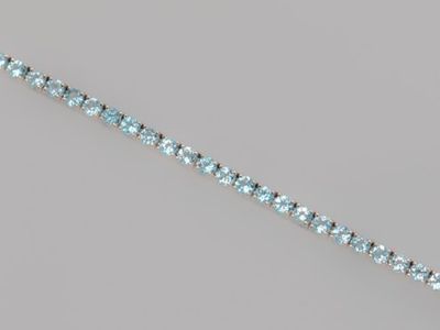 a close up of a blue topaz beaded bracelet on a gray surface