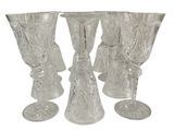 quatre verres à pied en verre transparent sont alignés sur une surface blanche