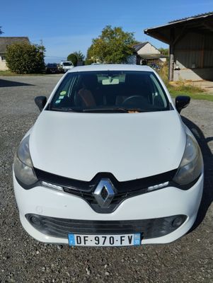 the front of a white car parked in a lot next to a building
