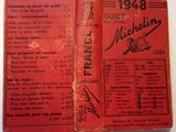 an old book with a red cover sitting on top of a table