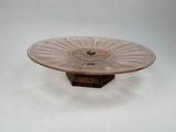 pink glass cake plate on stand on white surface with white background