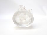 a glass vase with a bird inside of it on a white surface