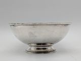 a silver bowl on a pedestal on a white surface