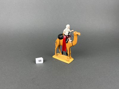 toy figurine of a man riding a camel with a dice in front of him