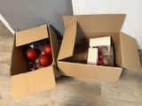 two boxes with christmas ornaments inside of them on the floor