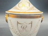 a close up of a white and gold covered bowl with a crest on it