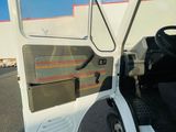 the door of a white truck with the driver ' s seat open