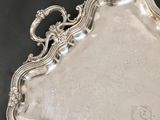 an antique silver tray with ornate design on a black surface
