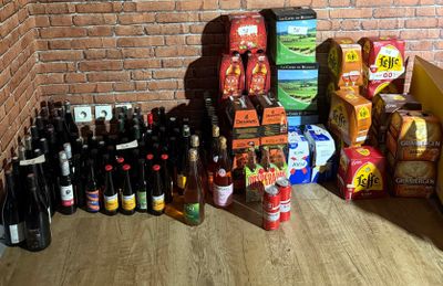 de nombreuses bouteilles de bière par terre, près d'un mur de briques