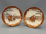 pair of chinese porcelain plates with figures on them on a gray background