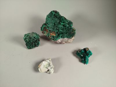 some green crystals and a rock on a white surface