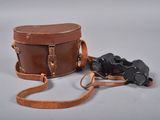 brown leather case with two binoculars attached to it
