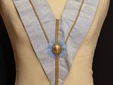 a close up of a mannequin with a blue sash and a gold necklace