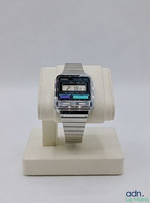 une montre numérique posée sur un socle, sur une surface blanche