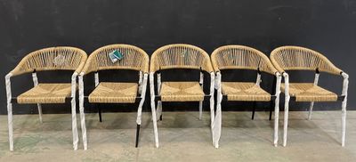 quatre chaises en osier sont alignées contre un mur noir
