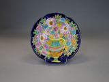 a blue and yellow plate with a vase of flowers on it