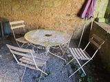 gravel patio area with table and chairs and umbrella in outdoor setting