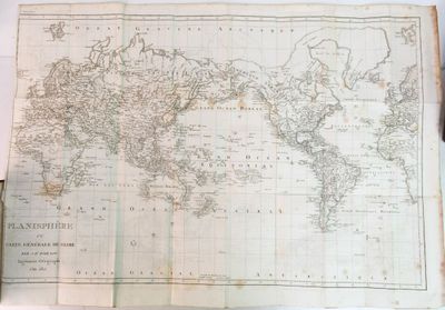 une vieille carte du monde sur laquelle est posé un stylo