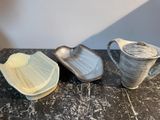three pieces of pottery sitting on a marble table