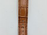 a close up of a watch on a white surface with a brown strap