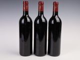 three bottles of red wine sitting next to each other on a white surface