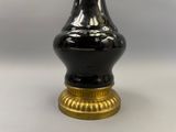 un vase noir avec un socle doré posé sur une table