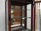 une vitrine avec des étagères en verre, dans un coin de la pièce