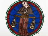 a stained glass picture of a lady holding a scale