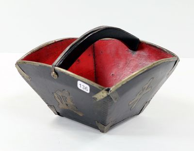 un petit bol noir et rouge posé sur une surface blanche