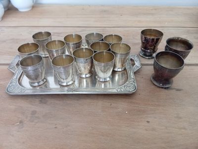 a tray of silver cups and a tray of silver cups on a wooden table