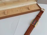 gucci watch in a box on a table with a leather strap