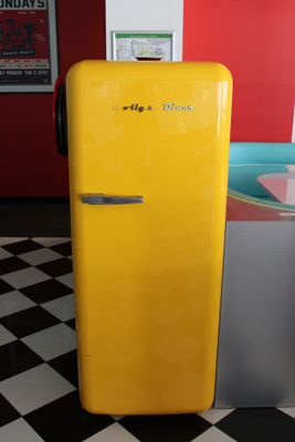 un réfrigérateur jaune posé au milieu d'un sol à carreaux noirs et blancs
