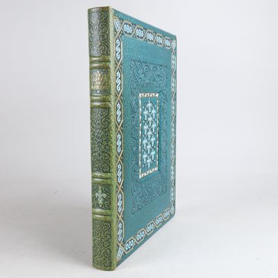 an old book with a blue cover sitting on top of a white table