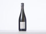 a bottle of wine sitting on top of a table next to a white wall