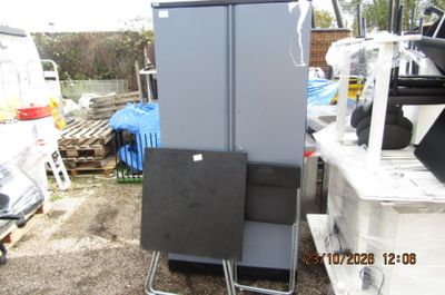 un réfrigérateur placé à côté d'une chaise dans un jardin