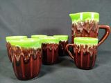 four brown and green coffee mugs sitting on top of a black table