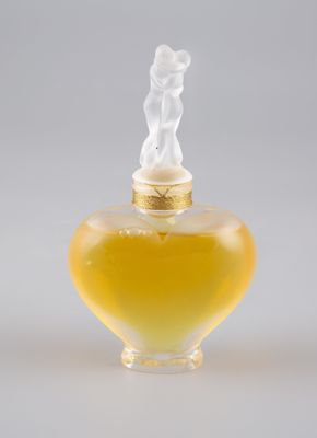 flacon de parfum en verre jaune surmonté d'une petite figurine