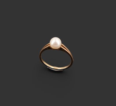 une bague en or sertie d'une perle sur fond noir