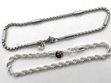 two silver chains on a white surface with a black bead
