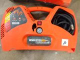 an orange air compressor sitting on top of a cement floor next to a blower