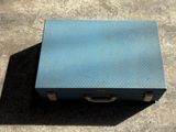 a small blue suitcase sitting on a concrete floor
