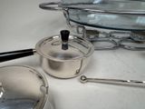 pots and pans sitting on a counter with a glass shelf behind them
