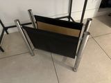a black magazine holder sitting on the floor next to a chair