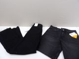 two pairs of black jeans sitting on top of a white table