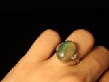 a person holding a ring with a green stone on it