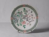 une assiette blanche ornée d'un motif vert et rouge