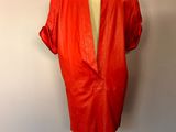une veste en cuir rouge posée sur un mannequin devant un mur