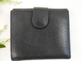 a black leather wallet sitting on top of a table next to a plant