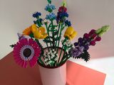 des fleurs aux couleurs vives dans un vase blanc posé sur une table rouge