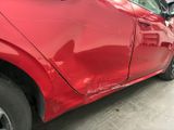 a red car that has been dented and is parked in a garage